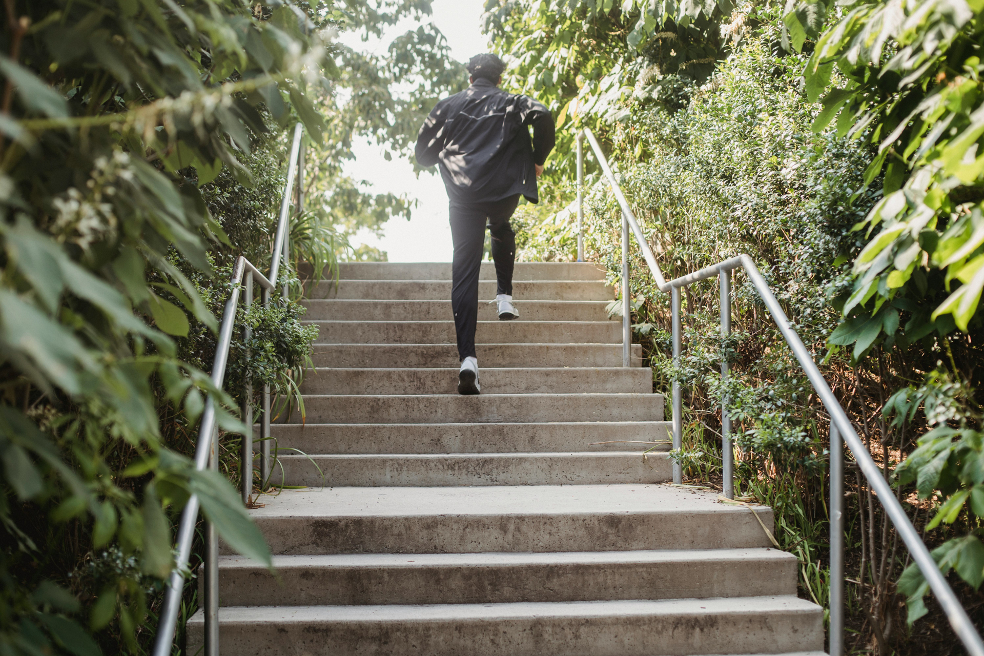 How to break free from limiting patterns: man running up outdoor stairs surrounded by greenery, symbolizing building momentum and overcoming barriers through functional fitness.