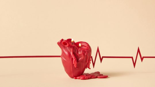 Melting red heart-shaped candle with flames, placed over a heartbeat line, symbolizing the importance of lifestyle change to reverse heart disease.