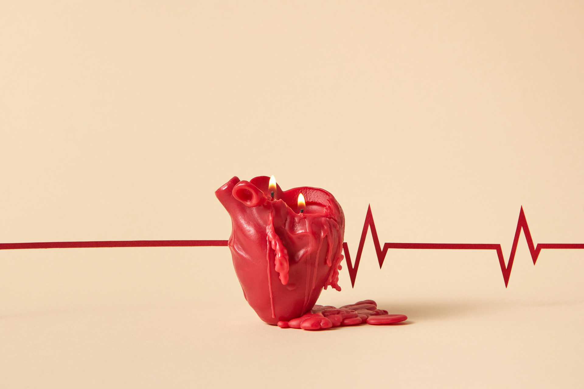Melting red heart-shaped candle with flames, placed over a heartbeat line, symbolizing the importance of lifestyle change to reverse heart disease.