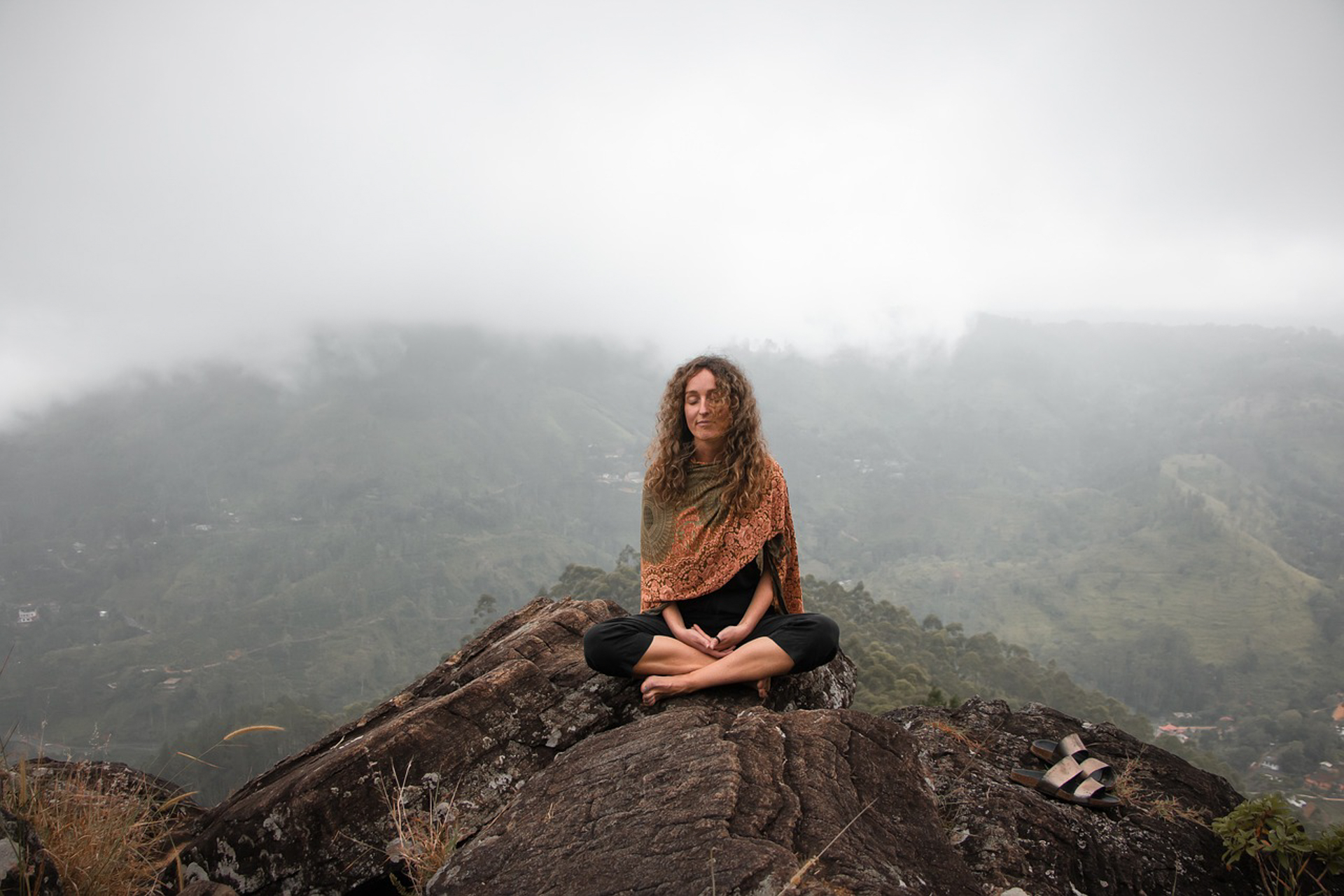 Woman meditating on a mountaintop, symbolizing natural blood pressure management through mindfulness and calm.