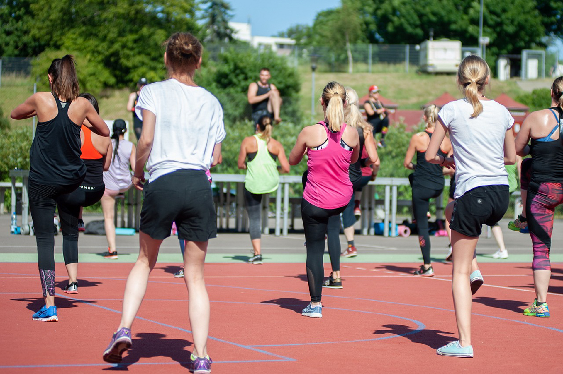 Women exercising outdoors in a group fitness class, performing dynamic movement that balances blood sugar and improves overall metabolic health.